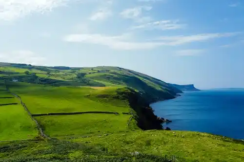 Soft sunrise horizon with a walking path along green coastal landscape